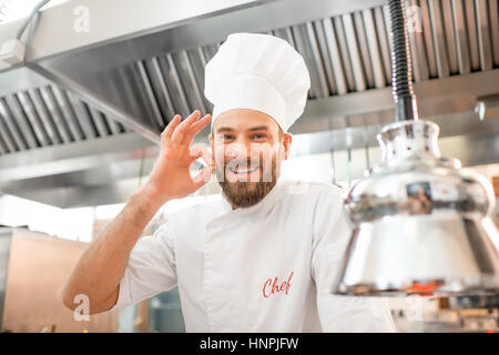 Porträt einer schönen Chef-Koch in uniform zeigt köstliche Zeichen in der Restaurantküche Stockfoto