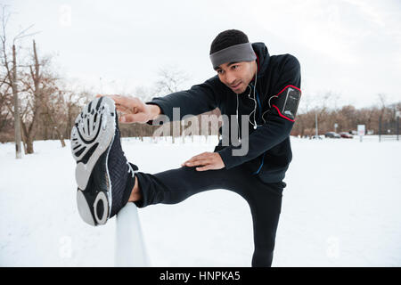 Porträt eines afrikanischen Fitness Mannes dehnen Beine vor dem laufen im Freien im winter Stockfoto