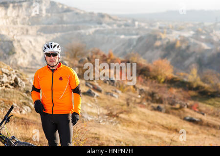 Mann in Helm und Brille Aufenthalt unter Landschaft mit Felsen und Hügel. Stockfoto