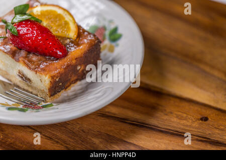 Obstkuchen mit Erdbeere und Zitrone auf Untertasse mit Gabel auf Holztisch Stockfoto