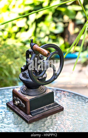 Vintage Kaffeemühle auf Tisch über Garten der Hintergrund jedoch unscharf. Stockfoto