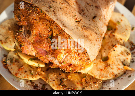 Marinierte Schweinshaxe mit in Scheiben geschnittenen Quitten, Gewürze und Kräuter closeup Stockfoto