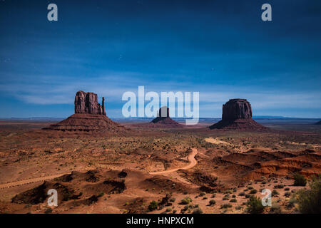 Klassische Panoramablick auf malerischen Monument Valley mit dem berühmten Fäustlinge und Merrick Butte in einer sternenklaren Nacht in schönem mystische Mondschein beleuchtet Stockfoto