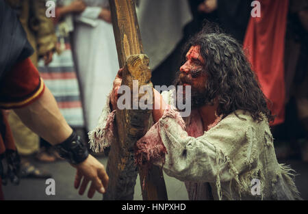 Schauspieler spielt Verwundeten müde Jesus Christus mit großen Holzkreuz während die Nachstellung des Kummers Weg am 15. April 2014, Bukarest, Rumänien Stockfoto