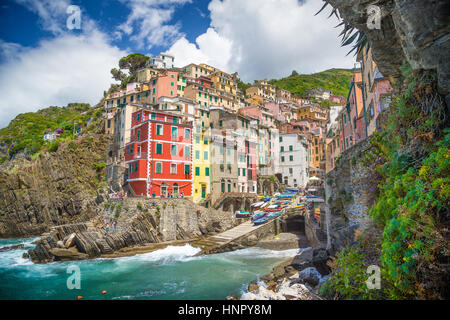 Klassische Ansicht der schönen Riomaggiore, eines der fünf berühmten malerischen Fisherman Dörfer der Cinque Terre, an einem sonnigen Tag mit blauem Himmel und Wolken Stockfoto