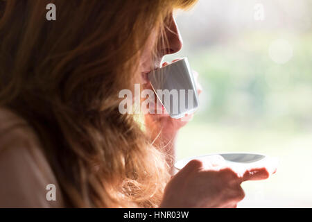 Eine Frau hält eine Tasse Kaffee in einem blauen Becher. Stockfoto