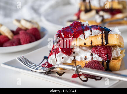 Belgische Waffeln mit Himbeeren und Sahne auf weißen Teller. Stockfoto