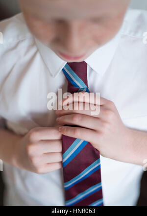 Ein Schuljunge seine Schule einheitliche Krawatte befestigen. Stockfoto