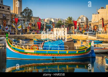 St.Julian es, Malta - traditionelle bunte Luzzu Fischerboot an der Spinola Bay bei Sonnenaufgang Stockfoto