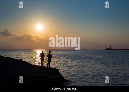 Valletta, Malta - in den frühen Morgenstunden zwei Fischer warten auf einen Happen an Sliema Tigné Punkt mit Wellenbrecher Leuchtturm im Hintergrund Stockfoto