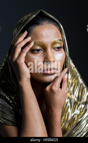 junge Frau gekleidet in Gold posiert für die Kamera Stockfoto