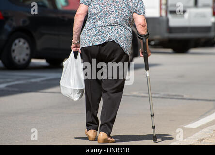 Ältere Frau mit Krücke auf der Straße. Stockfoto