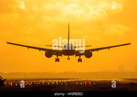 Flugzeug landet bei Sonnenaufgang. Foto an einem bewölkten frühen Morgen gemacht. Stockfoto