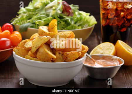 Geröstete Kartoffeln mit Dip und frischem Salat auf Holztisch Stockfoto