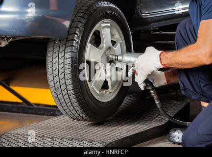 Techniker Schrauben Autoreifen mit pneumatischen Schraubenschlüssel Stockfoto