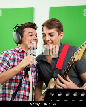 Sänger mit Mikrofon und Gitarre, die in der Aufzeichnung Studi Stockfoto