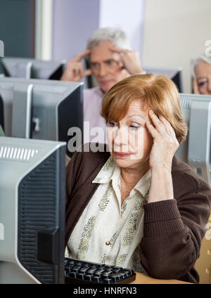 Angespannt ältere Frau auf der Suche nach Computer im Klassenzimmer Stockfoto