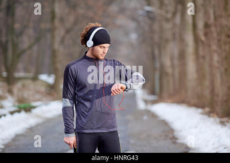 Mann in Sportbekleidung Joggen mit Kopfhörern Blick auf seinen Ausgang Stockfoto
