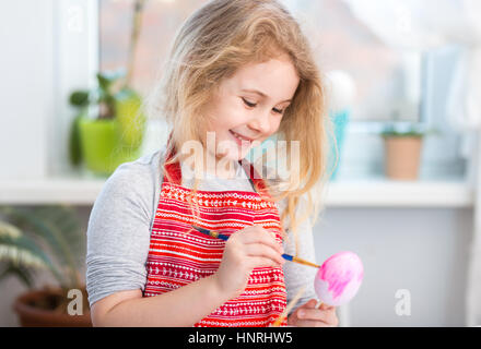 Kleine blonde Mädchen Färbung Eiern für Osterurlaub zu Hause Stockfoto