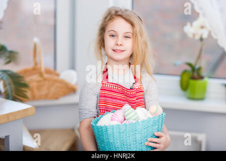 Kleine blonde Mädchen hält Korb mit bemalten Eiern. Ostern-Tag. Stockfoto