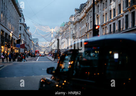 Traditionellen schwarzes Taxi wartet auf eine Ampel unter funkelnden Weihnachtsbeleuchtung in der Regent Street, London am Weihnachtstag, Dezember 2016 Stockfoto