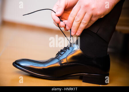 Bräutigam setzen seine Hochzeitsschuhe. Nahaufnahme der Hände. Stockfoto