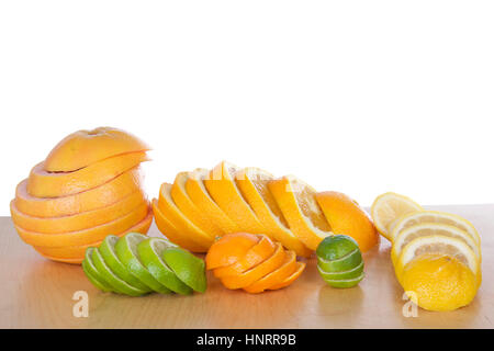 Bunte Scheiben Zitrus aufgereiht in Stapeln auf leichte braune Holz Tisch mit einem weißen Hintergrund. Marine Orange, Zitrone, Limette, Grapefruit, Cuties clementine Stockfoto