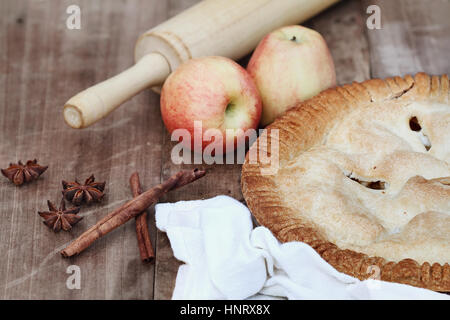 Hausgemachter Apfelkuchen Dessert mit Nudelhölzer und Zutaten über eine hölzerne Tischplatte. Extrem geringe Schärfentiefe. Stockfoto