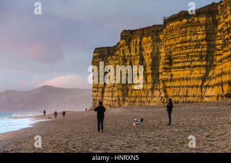 Burton Bradstock, Dorset, UK.  15. Februar 2017.  Großbritannien Wetter.  Hund Spaziergänger genießen die letzte von der Nachmittagssonne, die die goldenen Klippen am Bienenstock Strand von Burton Bradstock in Dorset mit Dusche dunkle Wolken im Westen bei Sonnenuntergang beleuchtet.  Bildnachweis: Graham Hunt/Alamy Live-Nachrichten Stockfoto