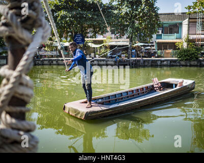 Thepharak, Samut Prakan, Thailand. 16. Februar 2017. Ein Fährmann zieht sein kleine Boot, die er als eine Fähre in Khlong Samrong, am Stadtrand von Bangkok benutzt. Der Bootsmann zieht es über ein System von Seilen und Rollen. Er arbeitet auf dem Boot, seit er ein Kind war. Kleine Fähren wie dies früher häufig in Bangkok aber viele Khlongs (die Kanäle, die verwendet, um Bangkok zu durchkreuzen) ausgefüllt und Brücken über die verbleibenden Khlongs wurden. Jetzt gibt es nur eine Handvoll Fähren links. Diese Fähre lädt 2 Baht (das Äquivalent von ca.. 06¢ US) pro Person zu Tak Stockfoto