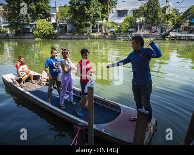 Thepharak, Samut Prakan, Thailand. 16. Februar 2017. Ein Fährmann bringt Passagiere in Khlong Samrong in seinem kleinen Boot, die er als eine Fähre, die in den Vororten von Bangkok benutzt. Der Bootsmann zieht es über ein System von Seilen und Rollen. Er arbeitet auf dem Boot, seit er ein Kind war. Kleine Fähren wie dies früher häufig in Bangkok aber viele Khlongs (die Kanäle, die verwendet, um Bangkok zu durchkreuzen) ausgefüllt und Brücken über die verbleibenden Khlongs wurden. Jetzt gibt es nur eine Handvoll Fähren links. Diese Fähre lädt 2 Baht (umgerechnet ca.. 06¢ US) pro Stockfoto