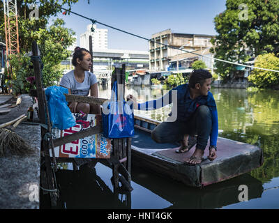 Thepharak, Samut Prakan, Thailand. 16. Februar 2017. Ein Fährmann, der seinem kleinen Boot verwendet wie eine Fähre und seine Freundin auf Fahrgäste am Khlong Samrung am Stadtrand von Bangkok warten. Der Bootsmann zieht es über ein System von Seilen und Rollen. Er arbeitet auf dem Boot, seit er ein Kind war. Kleine Fähren wie dies früher häufig in Bangkok aber viele Khlongs (die Kanäle, die verwendet, um Bangkok zu durchkreuzen) ausgefüllt und Brücken über die verbleibenden Khlongs wurden. Jetzt gibt es nur eine Handvoll Fähren links. Diese Fähre lädt 2 Baht (umgerechnet etwa.06 Stockfoto