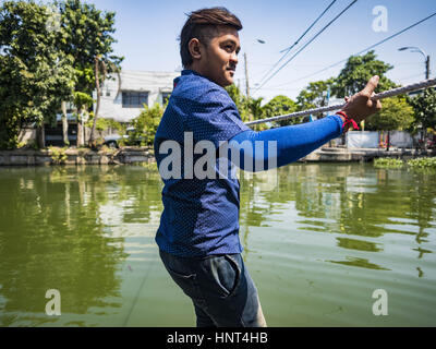 Thepharak, Samut Prakan, Thailand. 16. Februar 2017. Ein Fährmann zieht sein kleine Boot, die er als eine Fähre in Khlong Samrong, am Stadtrand von Bangkok benutzt. Der Bootsmann zieht es über ein System von Seilen und Rollen. Er arbeitet auf dem Boot, seit er ein Kind war. Kleine Fähren wie dies früher häufig in Bangkok aber viele Khlongs (die Kanäle, die verwendet, um Bangkok zu durchkreuzen) ausgefüllt und Brücken über die verbleibenden Khlongs wurden. Jetzt gibt es nur eine Handvoll Fähren links. Diese Fähre lädt 2 Baht (das Äquivalent von ca.. 06¢ US) pro Person zu Tak Stockfoto