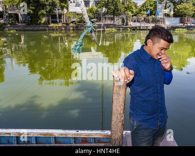 Thepharak, Samut Prakan, Thailand. 16. Februar 2017. Ein Fährmann, der seinem kleinen Boot als eine Fähre benutzt wartet auf Fluggäste am Khlong Samrung am Stadtrand von Bangkok. Der Bootsmann zieht es über ein System von Seilen und Rollen. Er arbeitet auf dem Boot, seit er ein Kind war. Kleine Fähren wie dies früher häufig in Bangkok aber viele Khlongs (die Kanäle, die verwendet, um Bangkok zu durchkreuzen) ausgefüllt und Brücken über die verbleibenden Khlongs wurden. Jetzt gibt es nur eine Handvoll Fähren links. Diese Fähre lädt 2 Baht (das Äquivalent von ca.. 06¢ US) pro Person Stockfoto