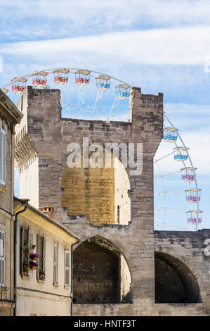 Sommer-Riesenrad gesehen durch eine malerische Straße in der Altstadt, umgeben von der mittelalterlichen Stadtmauer, Avignon, Frankreich Stockfoto