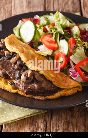 Österreichische Küche: Imperial Schnitzel mit Pilzen, Rührei und frischem Salat auf der Platte Nahaufnahme. vertikale Stockfoto