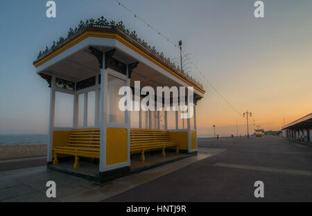 Eine öffentliche Unterschlupf und Sitzbank auf der ein Seafrount Roses in England, UK Stockfoto