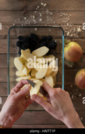 Eine Frau bereitet ein Fruchtpudding bröckeln. Schneiden Äpfel. Stockfoto
