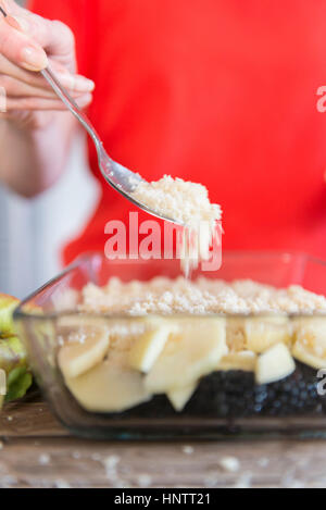 Eine Frau bereitet ein Fruchtpudding bröckeln. Prise bröckeln Richtfest. Stockfoto