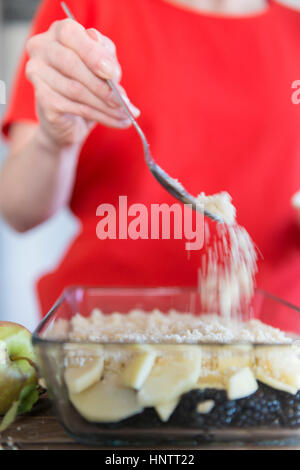 Eine Frau bereitet ein Fruchtpudding bröckeln. Prise bröckeln Richtfest. Stockfoto