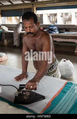 Man bügelt Kleider im historischen Dhobi Khana Laundry in Fort Kochi, Cochin, Kerala, Indien Stockfoto