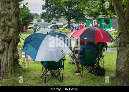 Teilnehmer und Zuschauer (im Regen) auf ein Krone grün-Bowling-Spiel auf dem Dorfplatz Bowling - Burley In Wharfedale, West Yorkshire, England. Stockfoto