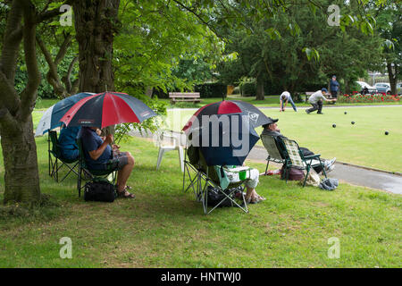 Teilnehmer und Zuschauer (im Regen) auf ein Krone grün-Bowling-Spiel auf dem Dorfplatz Bowling - Burley In Wharfedale, West Yorkshire, England. Stockfoto