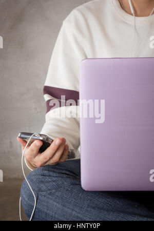 Frau sitzt auf dem Boden mit Laptop, Fotoarchiv Stockfoto