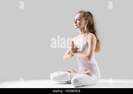 Junge attraktive Frau in Padmasana posieren mit Namaste, graue stud Stockfoto