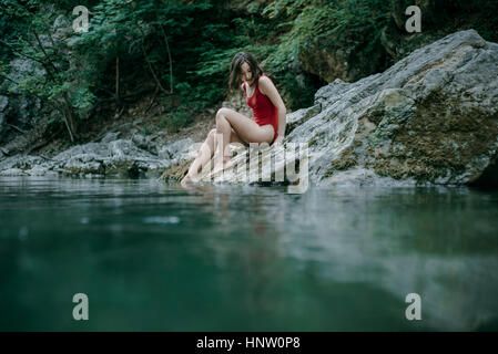 Kaukasische Frau sitzen auf den Felsen am Pool Wasser Stockfoto