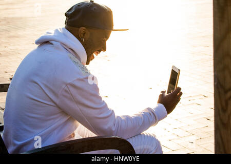 Schwarzer Mann SMS Lachen auf Handy Stockfoto