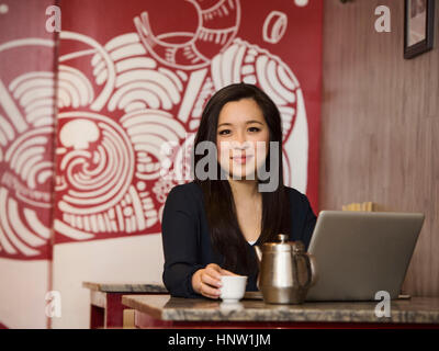 Chinesische Unternehmerin, Tee trinken und mit laptop Stockfoto