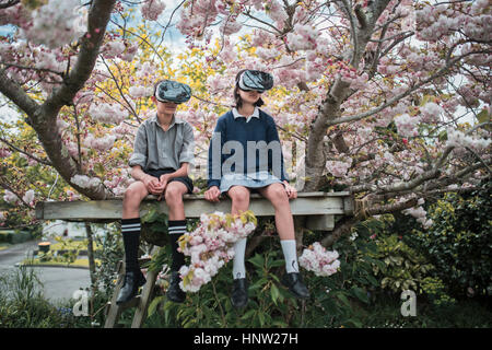 Gemischte Rennen-Bruder und Schwester sitzen im Baum virtual-Reality-Brille tragen Stockfoto