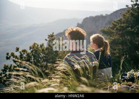 Kaukasische paar sitzt auf Hügel, malerische Aussicht bewundern Stockfoto